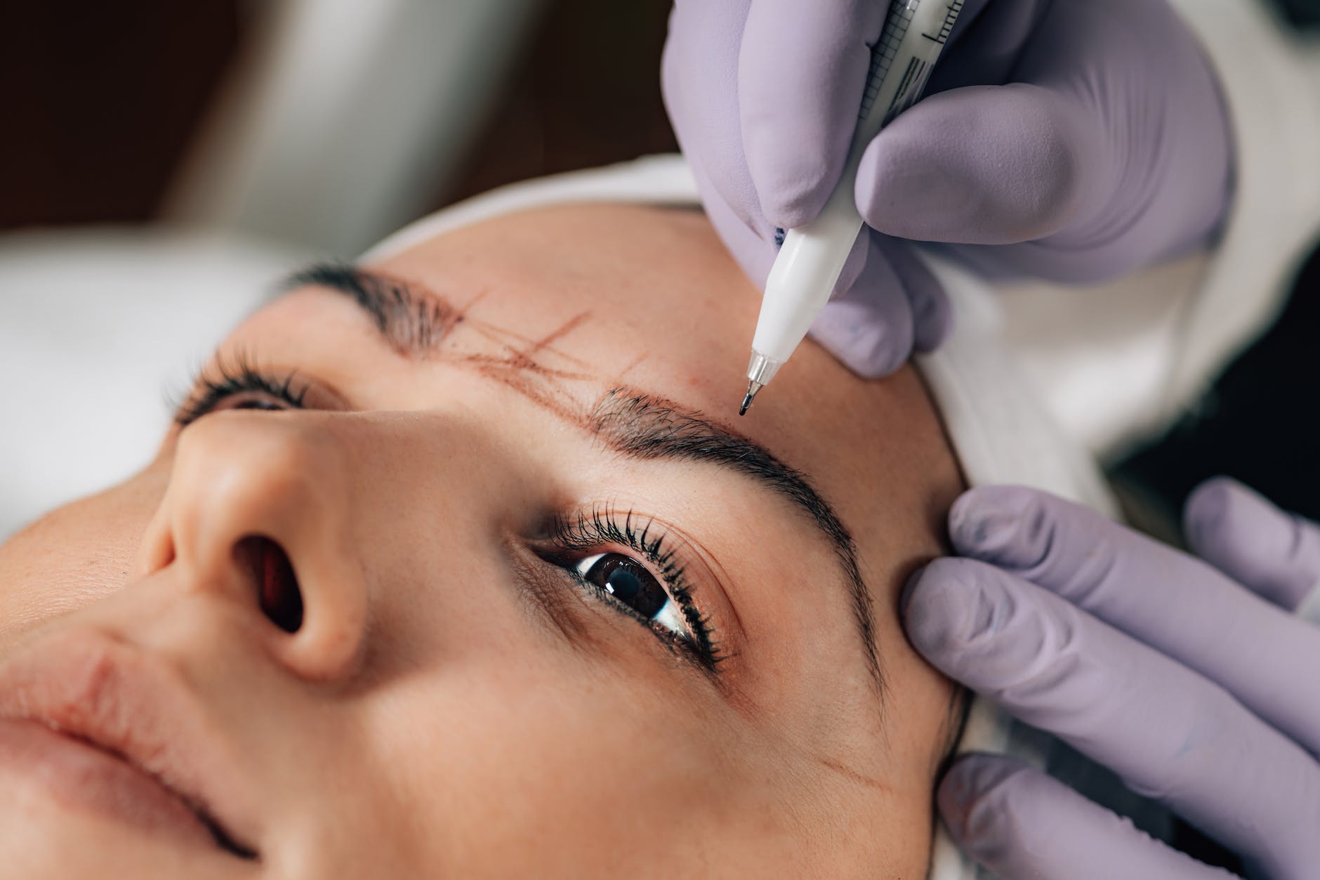 close up of beautician doing permanent brow tattoo